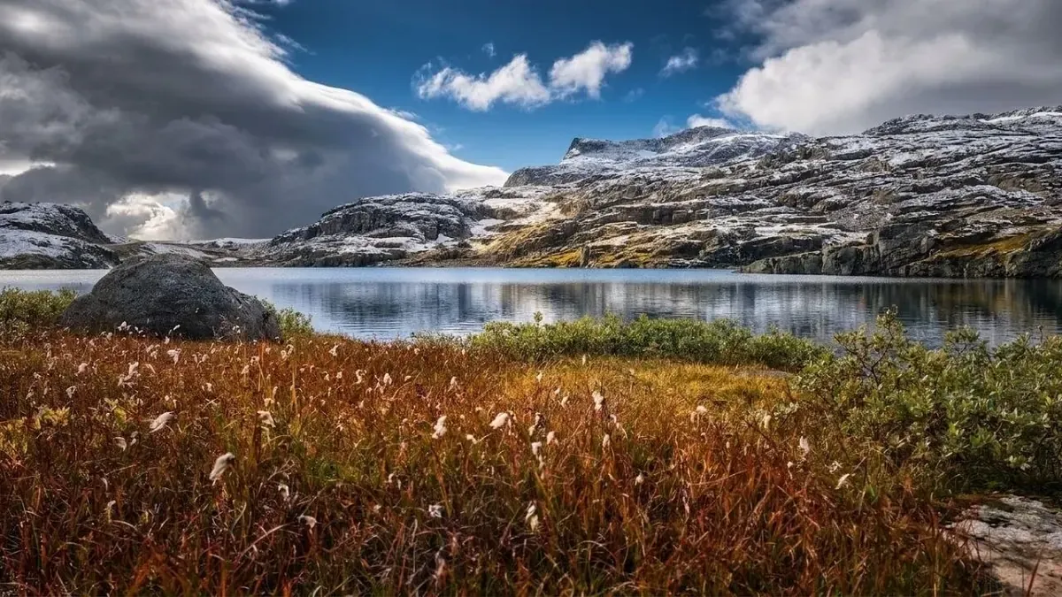 Bergsee mit Wollgras, Schneefeldern und wechselhaftem Wetter auf dem Aurlandsfjellet