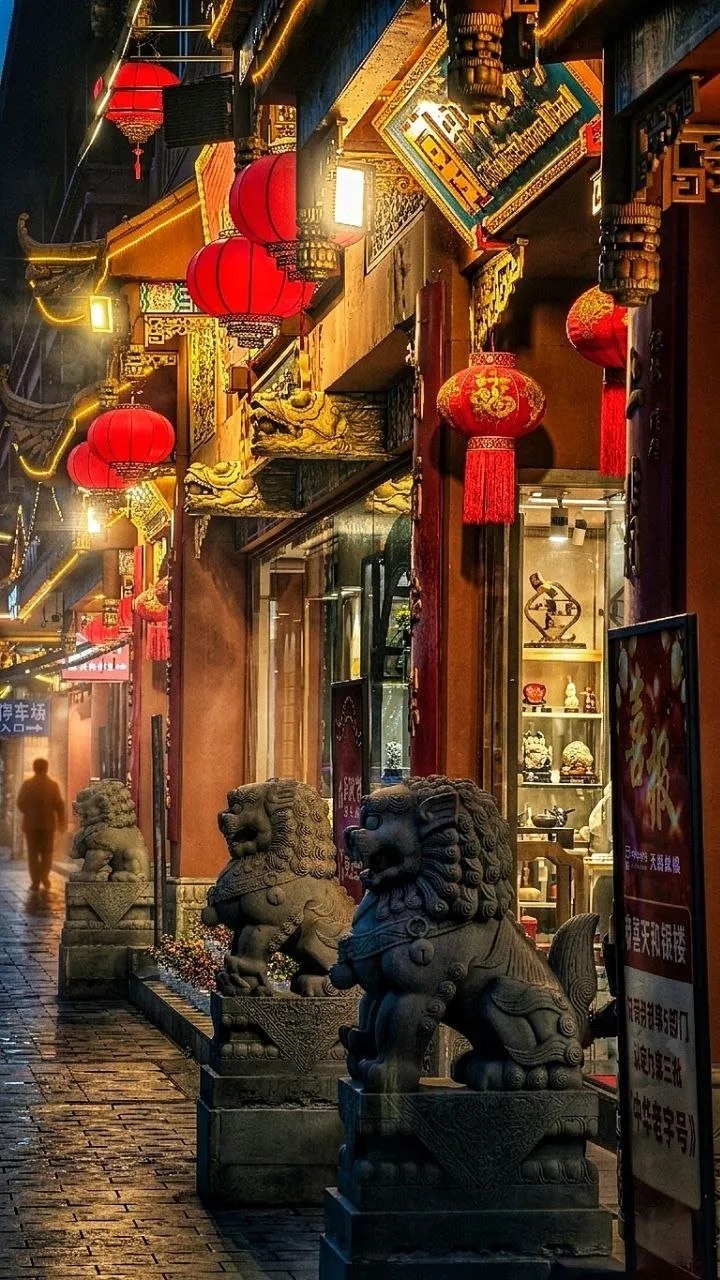 Enge Gasse mit roten Laternen und steinernen Löwen