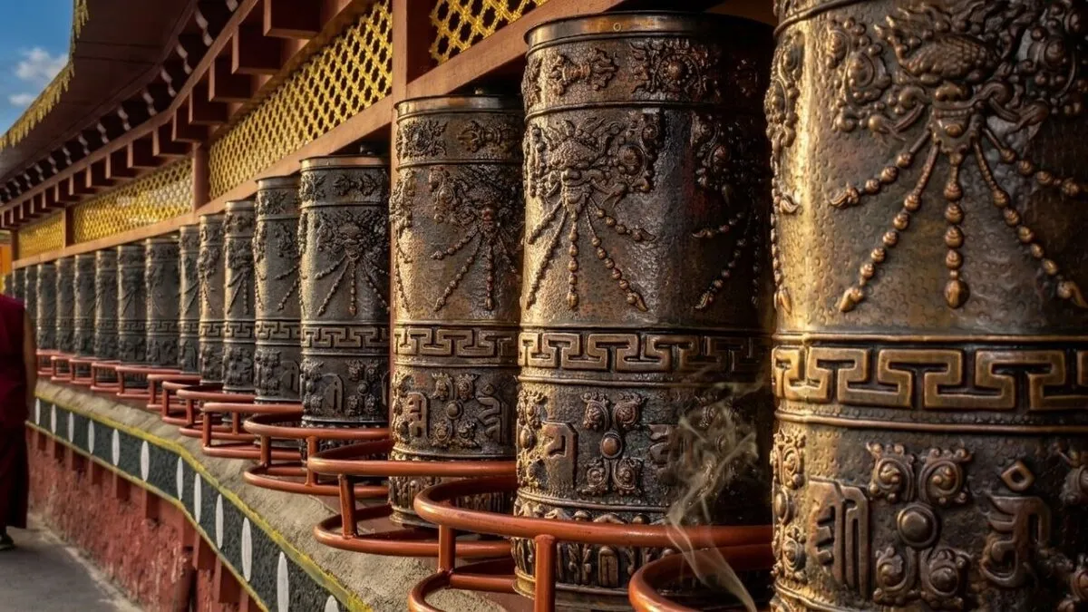 Reihe von großen, verzierten Gebetsmühlen aus Bronze am Wegesrand