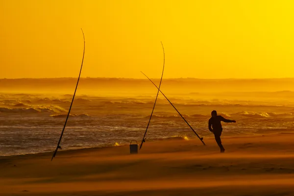 Angler am Strand bei Sonnenuntergang
